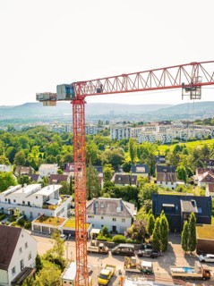 View of a large crane over a residential area in front of a mountainous landscape, construction
