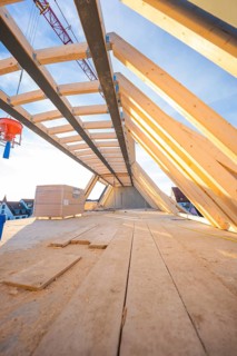 A wooden roof truss with an open sky above. Construction work is in progress, carpentry