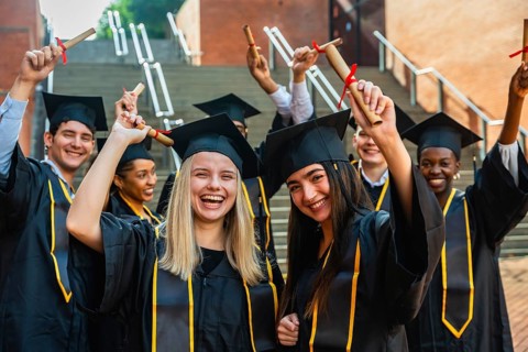 Group of happy diverse university students graduating, celebrating their academic achievement