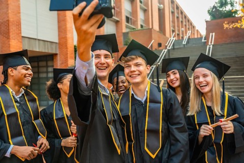 Group of smiling diverse students graduating from university, wearing academic caps and gowns,