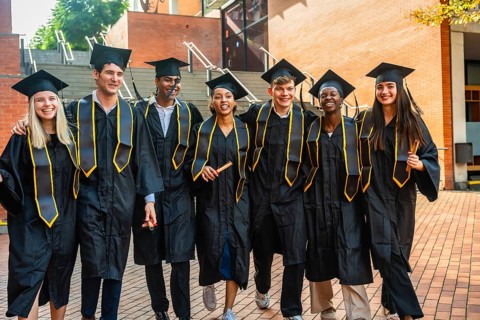 Diverse group of young adult students celebrating their university graduation, proudly wearing