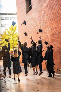 Diverse group of university students celebrating an achievement and success by throwing graduation