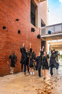 Group of happy diverse university graduates throwing their academic caps into the air and jumping