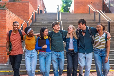 Group of happy young adult students from different ethnic backgrounds walking together on a