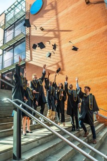 Diverse group of young adult university graduates celebrating a successful academic achievement by