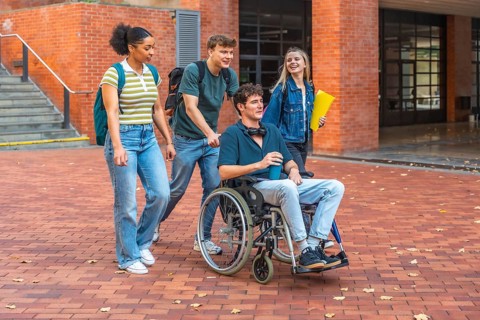 Young adult students walking and chatting on campus, diverse group including a male student in a