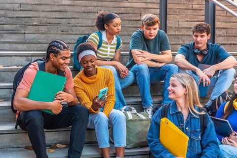 Diverse group of university students are relaxing and interacting on campus stairs, sharing moments