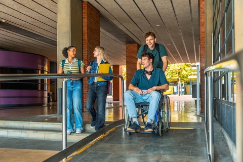 Young diverse students collaborating, navigating a modern university building ramp, showing