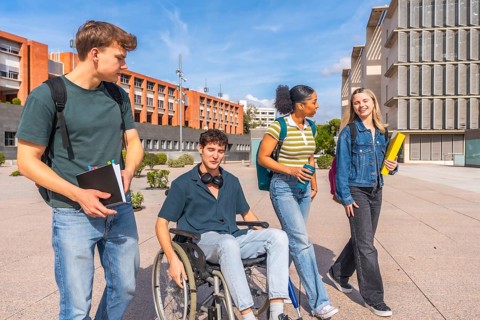 Diverse group of young students experiencing inclusion while walking and talking on a university