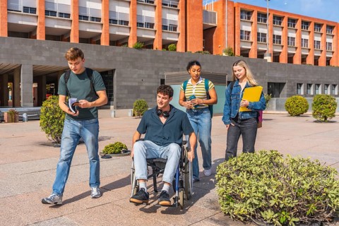 Group of diverse university students, including a young man in a wheelchair, walking together