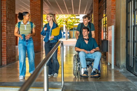 Group of young students, including one young man using a wheelchair, navigating an accessible