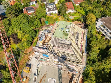 Roof of a house under construction with crane and surrounding houses in the countryside,