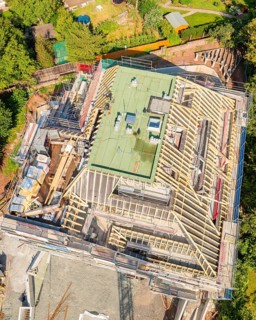 Bird's eye view of a building under construction in a green city scene, carpentry construction