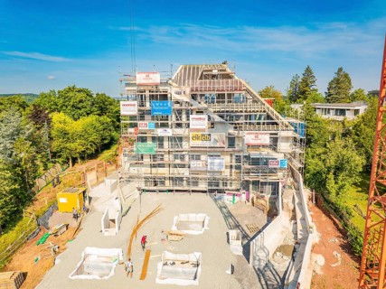 Large construction site with scaffolding around a multi-storey building and building materials on