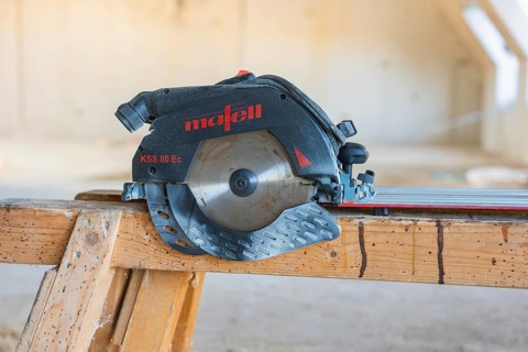 Close-up of a black and red circular saw on a wooden table, carpentry construction, roof extension,