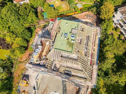 Bird's eye view of a building with roof structure, surrounded by green landscape, carpentry