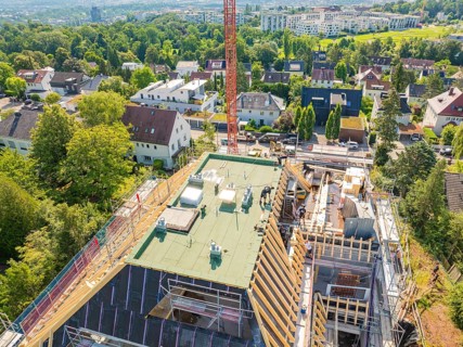 Panoramic view of a building under construction with crane and green surroundings, carpentry