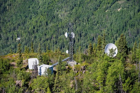 Transmission tower and satellite dishes and antennas between trees, Lion's Head, Chugach Mountains,