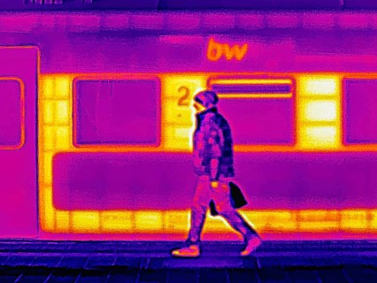 Locomotive in the train station. A man is walking on the platform. Thermal image or thermography,