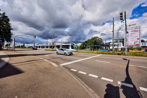 Tram, cars, street, sidewalk, lanes, cycle path, catenary masts, overhead line, central island,