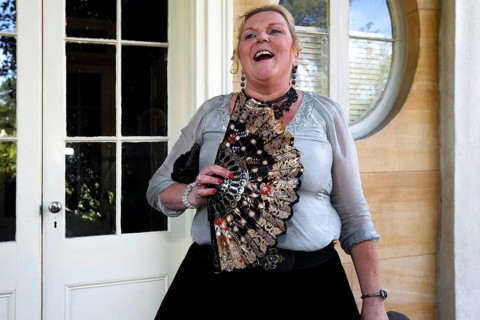 Laughing woman with decorative fan standing in front of an elegant entrance, Houmas House,