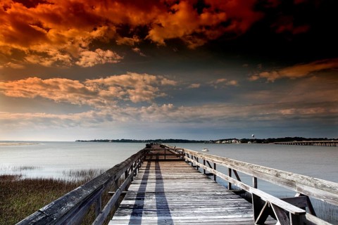 Long pier under a dramatically colored evening sky with clouds, Hunting Island, South Carolina, USA