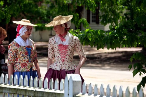 Women in period costumes with hats walking along Duke of Gloucester Street, Williamsburg, Virginia,