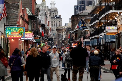 Bustling Bourbon Street at night with numerous passers-by and illuminated signs, New Orleans,
