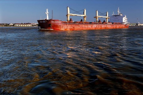 Cargo ship on a river with reflecting water and blue sky, New Orleans, Louisiana, USA