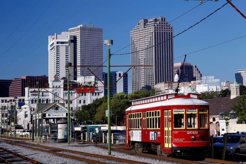 Red streetcar in front of city skyline with skyscrapers on a sunny day, New Orleans, Louisiana, USA