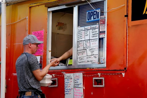 Person orders food from a colorful food truck full of menu boards, Natchez, Mississippi, USA