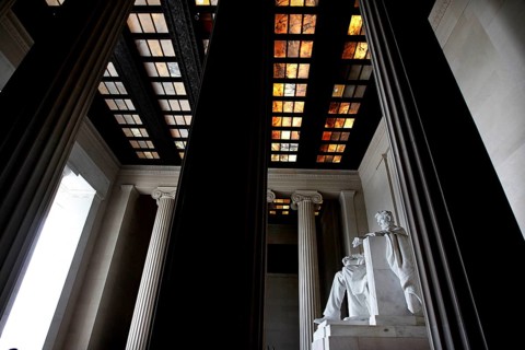 Monumental statue of Abraham Lincoln between tall pillars in a monumental building, Washington D.C,