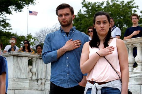 A man and a woman stand respectfully with their hands on their hearts during a ceremony, Washington