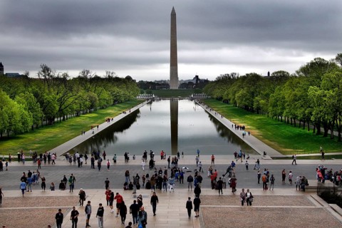 Visitors look at the Washington Monument across a reflecting pond, Washington D.C, USA