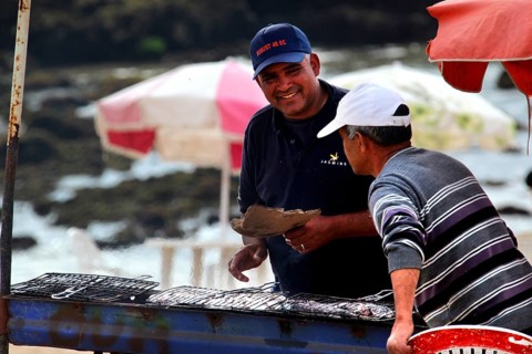 Two men talking at a food stall on the shore with a view of the sea, Oulidia, Doukkala-Abda,