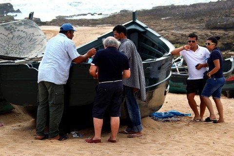 Group of people gather around a fishing boat on the beach in Oulidia, Oulidia, Doukkala-Abda,
