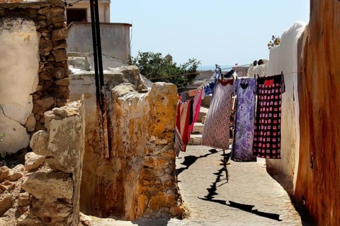 Narrow path between stone houses with colorful fabrics on clotheslines, Safi, Medina, Morocco