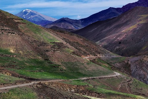 Barren mountain landscape with green valleys and a winding road in the High Atlas, Ouarzazate, High