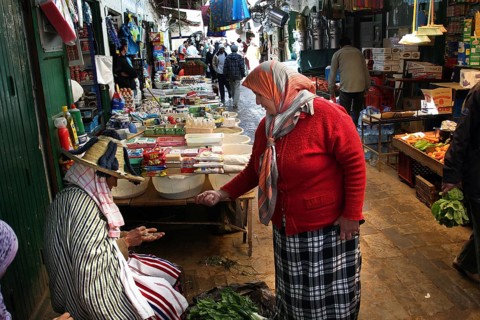 Two woman in traditional clothing talking at a busy market, Tetouan, Medina, Morocco