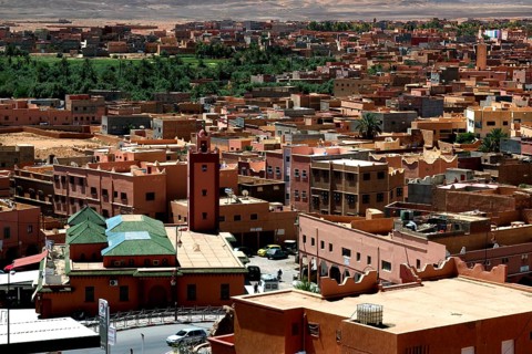 Townscape of Tinerhir with traditional buildings and green oasis behind them, Tinerhir, Morocco