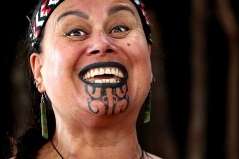 Smiling woman wearing a traditional Maori style moko, Rotorua, Whakarewarewa, New Zealand