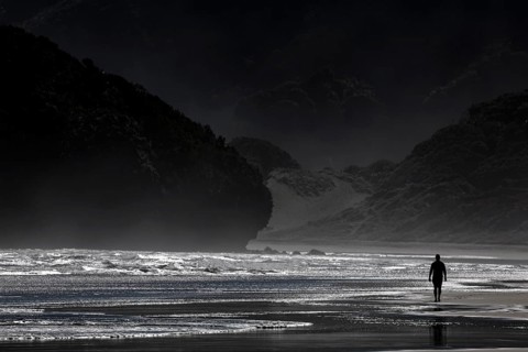 Person walking along the dramatic coastline of Bethells Beach, Te Henga, region, New Zealand