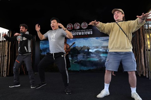 Three tourists taking part in a Haka performance and having fun on stage, Rotorua, Bay of Plenty,