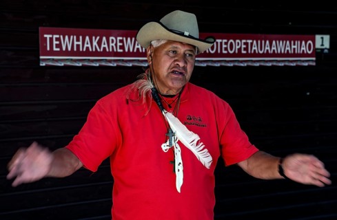 A Maori guide named Philipp explains Maori culture in a red and black outfit, Rotorua, Bay of