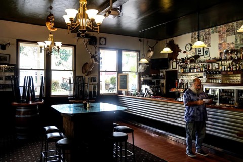 Atmospheric hotel bar with vintage decor and a man at the bar, Whangamomona, New Zealand