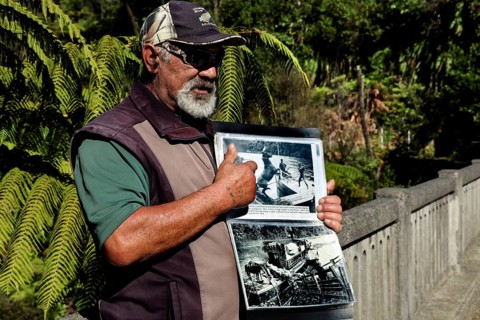 Man showing a book at the bridge in the thick forest on the Whanganui River, Whanganui River,