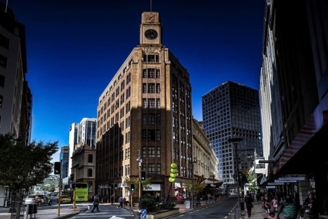 Historic building with clock tower and modern buildings in clear skies on Lambton Quay, Wellington,