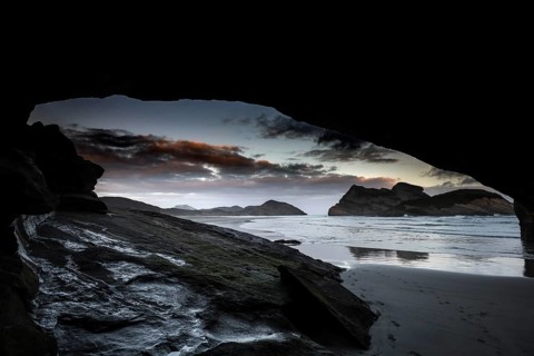 Dramatic coastal scene at Wharariki Beach with a view of the ocean from a cave, Wharariki Beach,