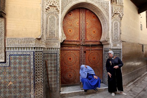 Two men in front of an artfully decorated wooden door with mosaic decoration, Fez, Fez el Bali,