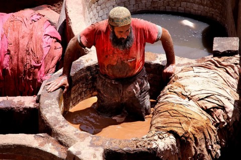 A worker in the tanners' quarter of Fez works on leather in a large paint basin, Fez, el-Bali,